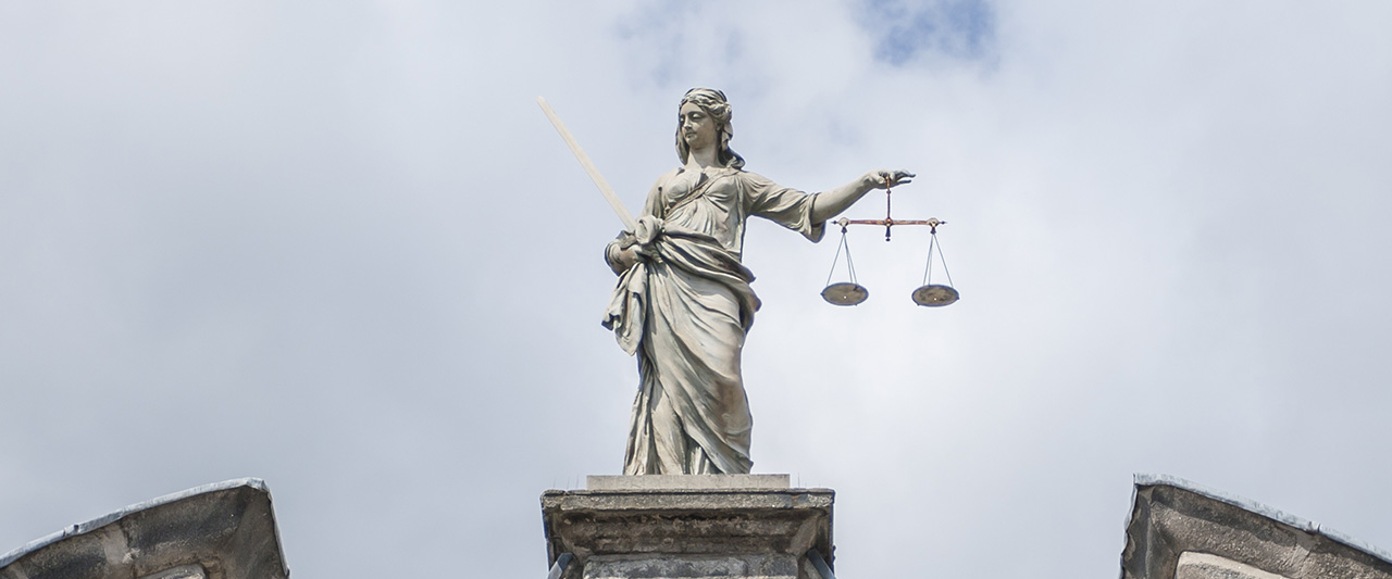 A stone statue of lady justice holding scales of justice